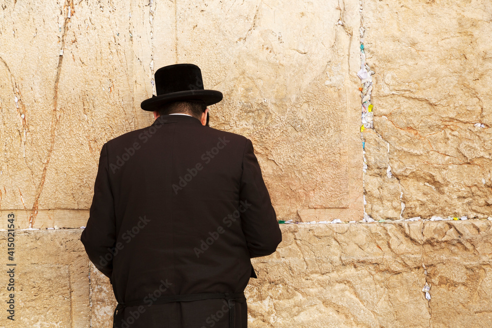 A Jewish man wearing Orthodox clothing prays by the Western Wall (Wailing Wall), Jerusalem, Israel A Jewish man wearing Orthodox clothing prays by the Western Wall (Wailing Wall), Jerusalem, Israel