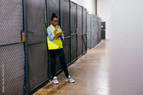 African American woman in datacenter surveying warehouse is secure photo