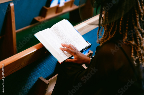 Woman sitting in pews and reading bible at church photo