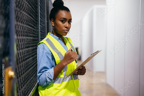 African American woman in datacenter surveying warehouse is secure photo