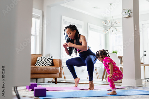 African American Mother and daughter doing yoga in living room