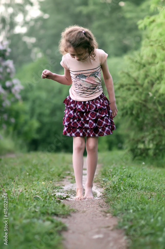 Barefoot girl walks through a puddles of water after the summer rain. © pictures_for_you