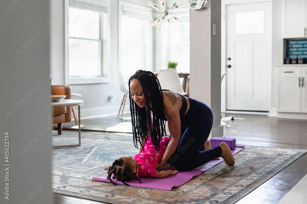 Black mom helps daughter practice yoga exercise together Black mom helps daughter practice yoga exercise together