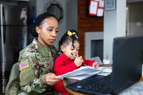 Focused military woman working from home at laptop photo