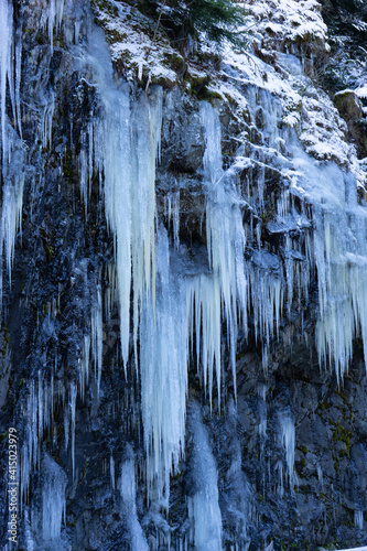 Rock cliff with ice stalactites in winter