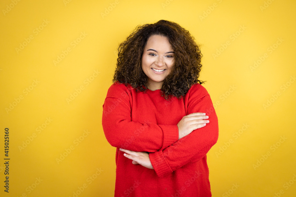 Young african american woman wearing red sweater over yellow background with a happy face standing and smiling with a confident smile showing teeth with arms crossed Young african american woman wearing red sweater over yellow background with a happy face standing and smiling with a confident smile showing teeth with arms crossed