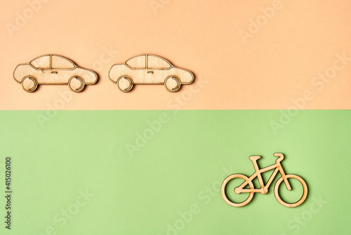 Wooden bicycle on green background ahead of cars - ecological transport concept photo