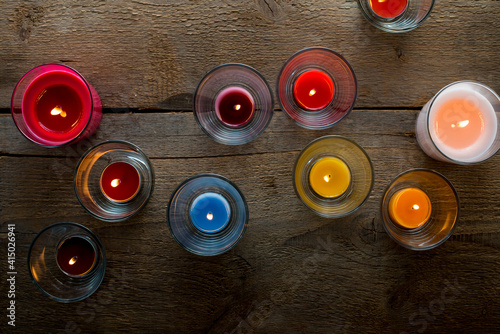 Colorful glass candles burning on wooden surface photo