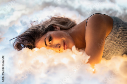 Smiling beautiful woman relaxing on illuminated cottons photo