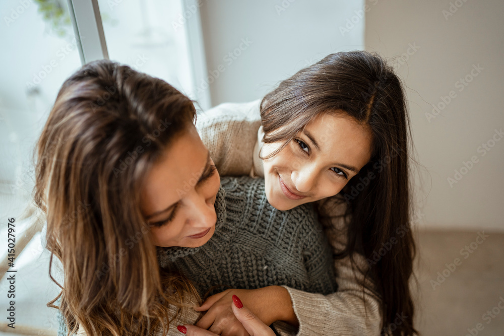 Smiling girl embracing mother at home Smiling girl embracing mother at home