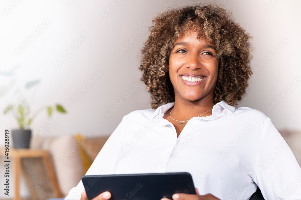Smiling woman with digital tablet looking away while sitting at home