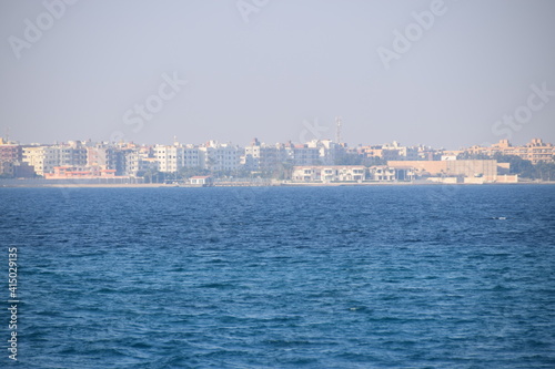 Fototapeta Naklejka Na Ścianę i Meble -  Hurghada disappears in the haze of the Red Sea, going by boat to the coral reef, view back, city skyline Hurgharda, Egypt