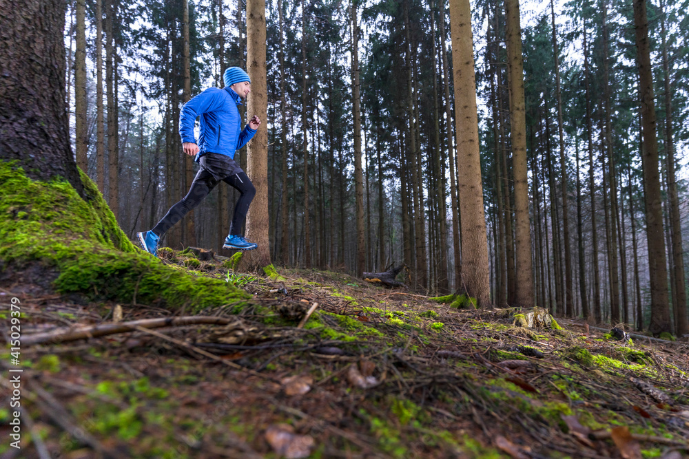 Male jogger running in coniferous forest during winter Male jogger running in coniferous forest during winter