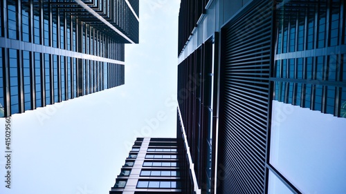 Bottom view of modern skyscrapers in business district against blue sky. Looking up at business buildings in downtown.