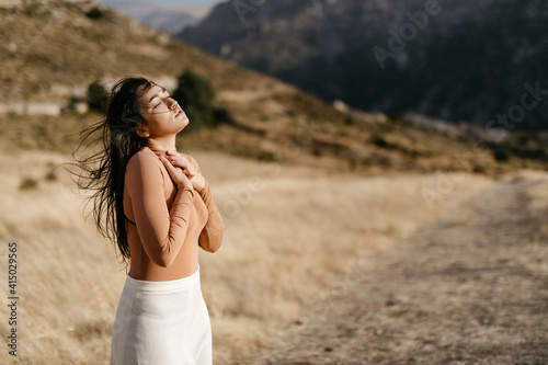 Young woman with eyes closed standing in field during sunset photo