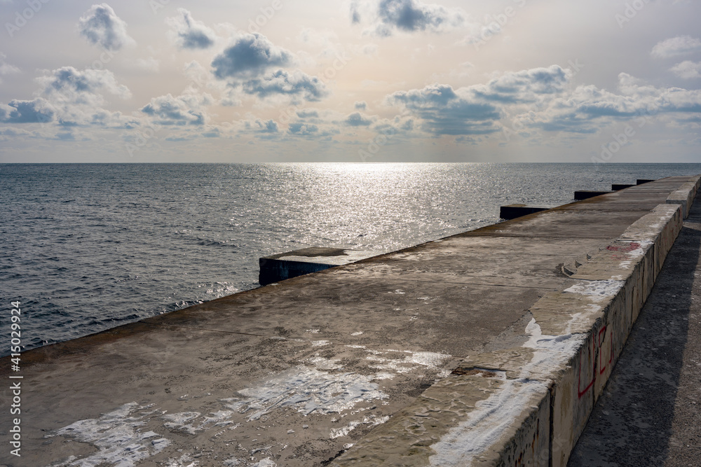 Empty concrete pier by the winter sea on a sunny day