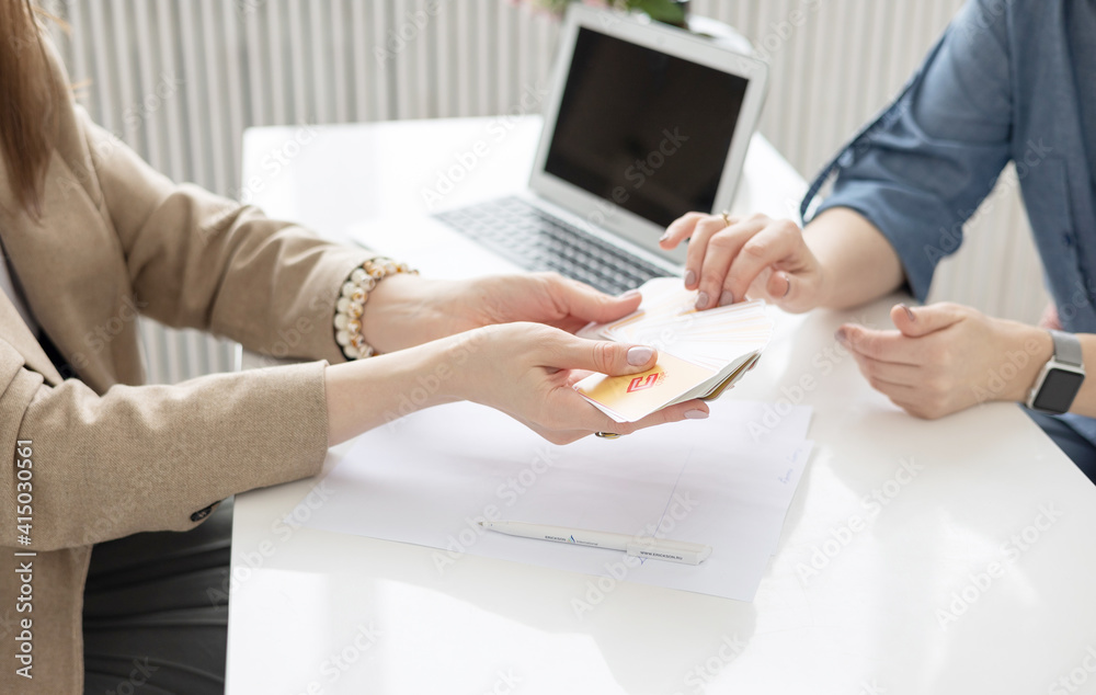 two young women conduct a coaching session in home office in light interior with laptop and flowers on tablework with metaphorical cards and psychological counseling two young women conduct a coaching session in home office in light interior with laptop and flowers on tablework with metaphorical cards and psychological counseling