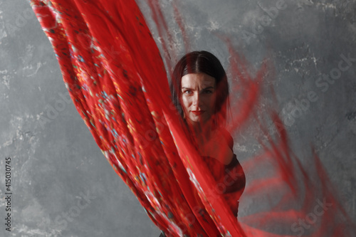 Young adult spanish woman dancing flamenco on gray vintage background with motion blur