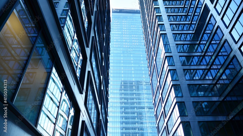 Bottom view of modern skyscrapers in business district against blue sky. Looking up at business buildings in downtown. Bottom view of modern skyscrapers in business district against blue sky. Looking up at business buildings in downtown.
