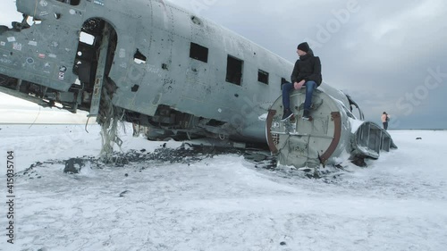 Tourists walk next to Slheimasandur dc 3 plane wreck in Iceland. Plane wreck around Vik  photo