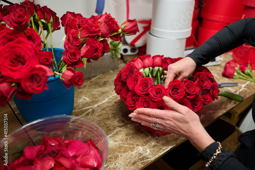 Foto Florist making flower box with red roses on the table, red roses in the tank on
