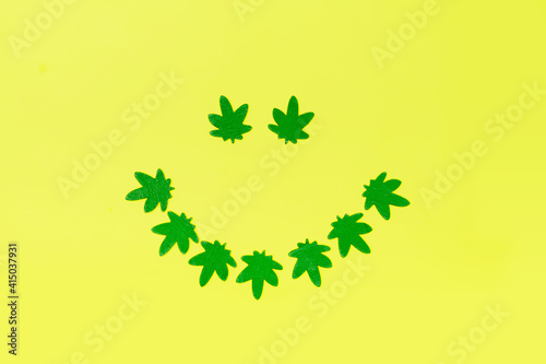 Smile made from green cannabis leaves. Smiling face symbol made with marijuana leaves. 