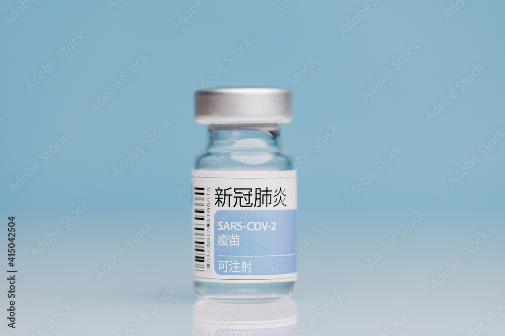 Glass vial with vaccine from COVID 19 placed on table on blue background