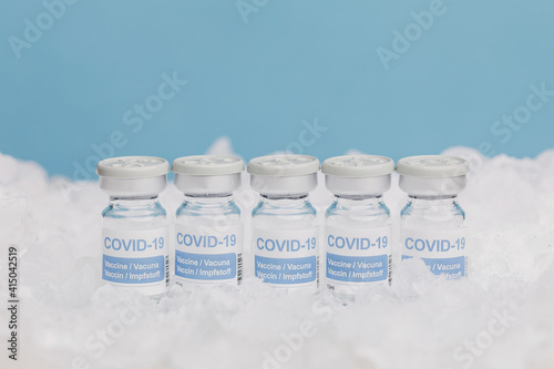 Closeup of glass vials with vaccine from COVID 19 placed on ice in freezer photo