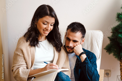 Content couple of musicians sitting together in armchair and taking notes while composing music at home