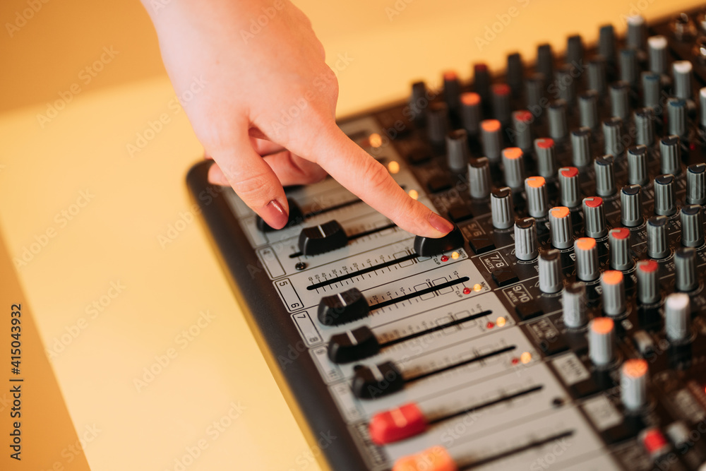 Crop hand of woman using equalizer in music studio on blurred background