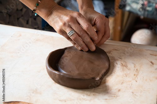 From above of crop anonymous male artisan rolling clay piece while creating plate in workshop photo