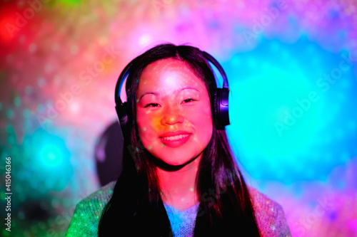 Wallpaper Mural Stock photo of young asian woman listening to music in her room with colorful lights and looking at camera. Torontodigital.ca