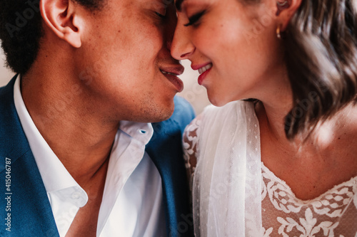 Crop young happy newlywed couple wearing posh wedding clothes sitting on floor face to face photo