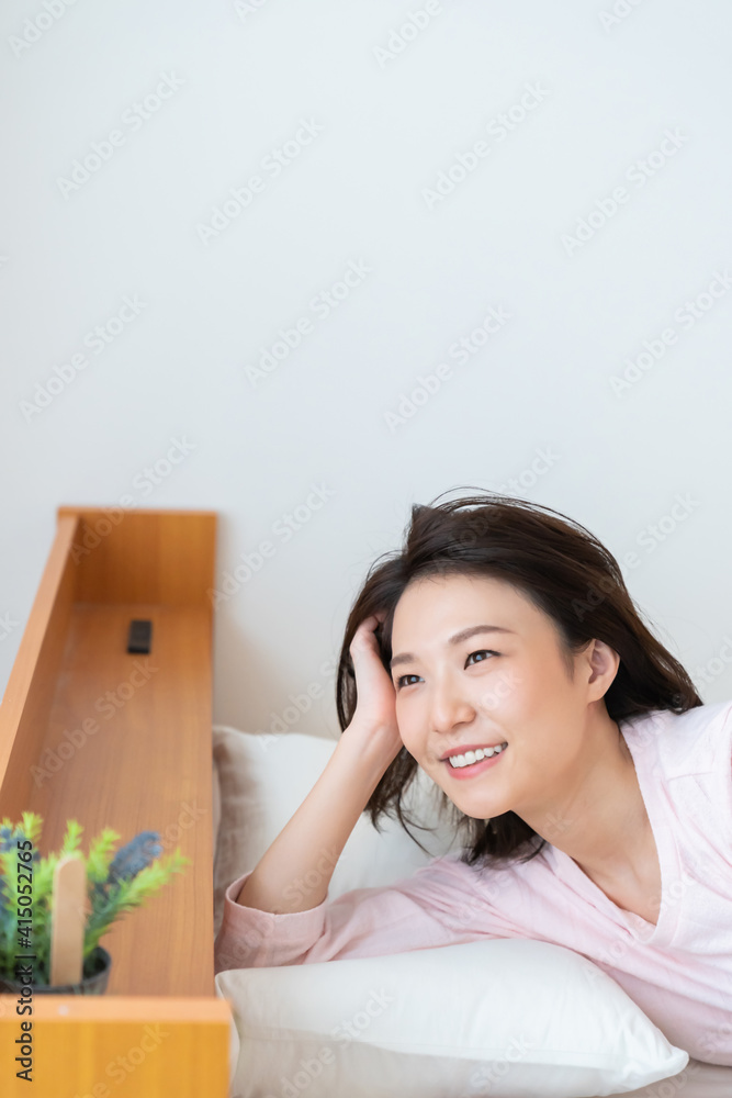 パジャマを着た女性　ベッド　笑顔