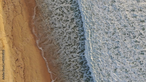 Vue aérienne des vagues sur la plage au coucher du soleil
