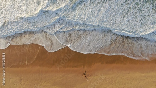 Vue aérienne des vagues et bâton sur la plage au coucher du soleil photo