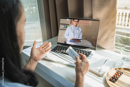 Asian chinese doctor or therapist help releave stress from coronavirus crisis video conference call online live talk remotely with Old woman sit on bed couch at home using labtop doctor consultation. photo