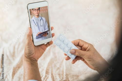 Asian doctor or therapist help releave stress from coronavirus crisis video conference call online live talk remotely with Old woman sit on bed couch at home using smartphone doctor consultation. photo