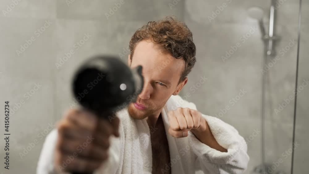 A handsome young man blows on himself with a hair dryer and imagines that he is a super man A handsome young man blows on himself with a hair dryer and imagines that he is a super man