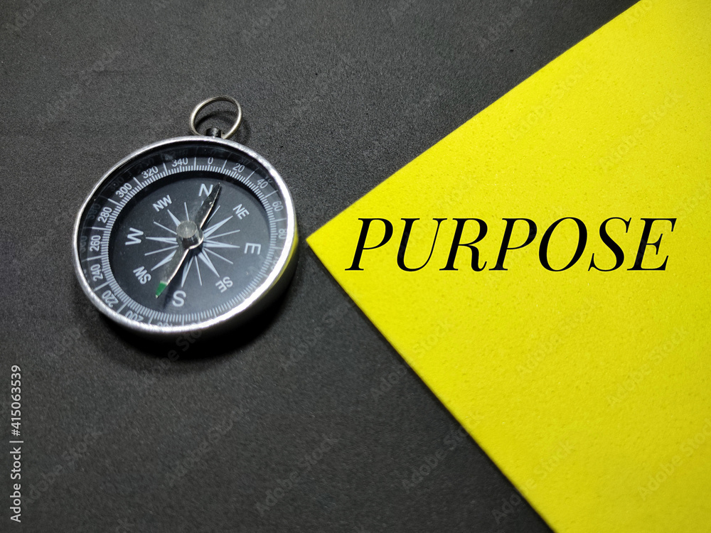 Selective focus.Word PURPOSE with compass on a colorful background.Shot were noise and film grain. Selective focus.Word PURPOSE with compass on a colorful background.Shot were noise and film grain.