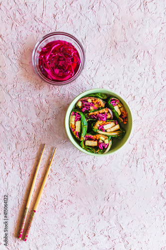 Bowl filled with colorful vegetarian swiss chard wraps near chopsticks