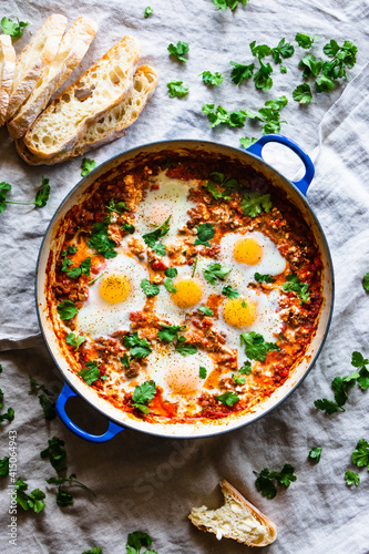 Photography Eggs in purgatory in skillet, ciabatta bread, and scattered cilantro