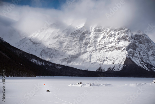 A couple of tents set up out on a frozen Kananaksis Lake used by ice fisherman during a beautiful day in the Canadian Rockies. photo