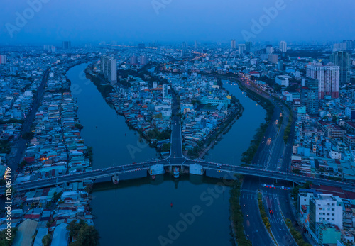 Aerial view of symmetrical french colonial traffic bridge at night across a canal in urban area with blue treatment