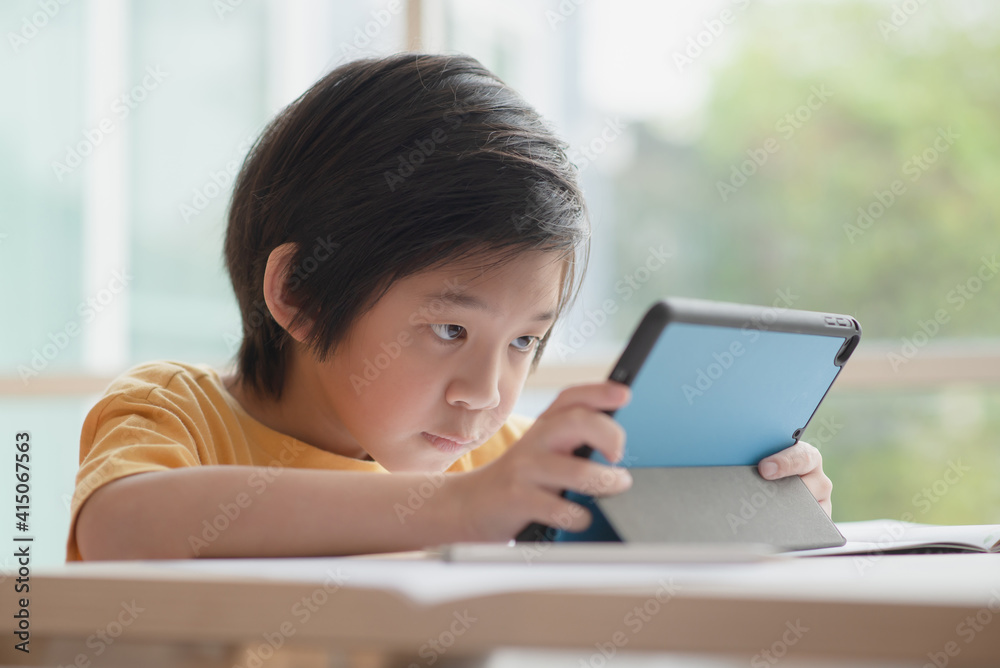 Child playing game on tablet with serious face Child playing game on tablet with serious face