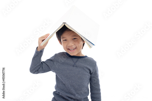 Cute Asian boy with book on head thinking on white background isolated