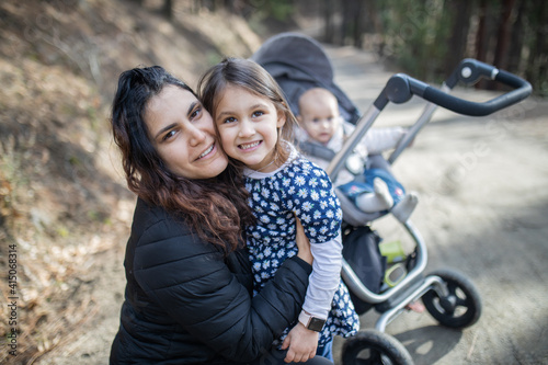 Happy woman with her adorable young daughters in the forest