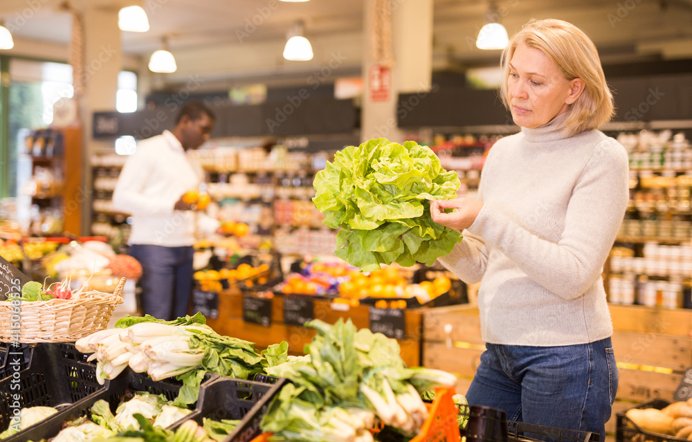 Portrait of pensive mature woman buying fresh organic vegetables in supermarket
