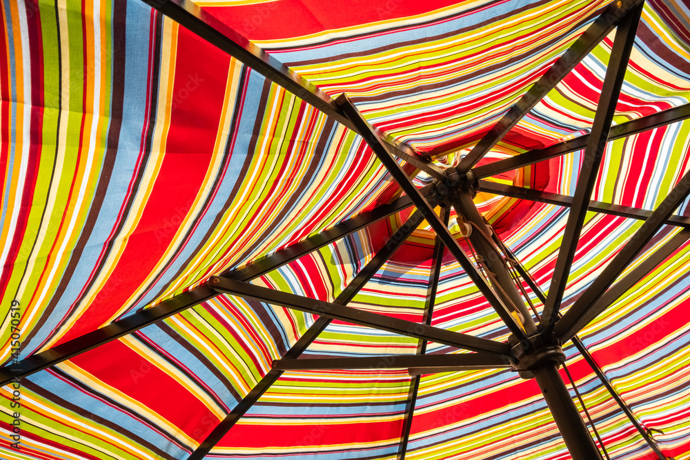 Abstract background with stripes...striped patio umbrella from the underside in the sun.