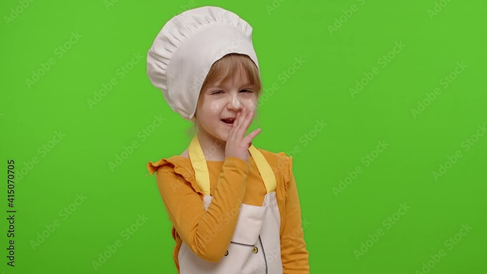 Child girl kid dressed as professional cook chef holding finger on her lips on chroma key background. Gesture of shhh, hush, secret, silence. Nutrition, cooking school, education, food. Fun and humor Child girl kid dressed as professional cook chef holding finger on her lips on chroma key background. Gesture of shhh, hush, secret, silence. Nutrition, cooking school, education, food. Fun and humor